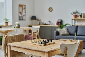 Chess board set up on table in living room / kitchen area. Intended to show casual setup for chess lessons at home