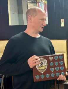 Photo of chess coach Cameron Smith holding a trophy at the Troon Chess Club annual prizegiving 2024